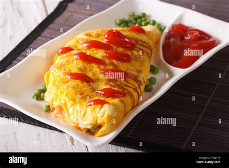 Delicious Omurice omelette with ketchup close-up on a plate. Horizontal ...