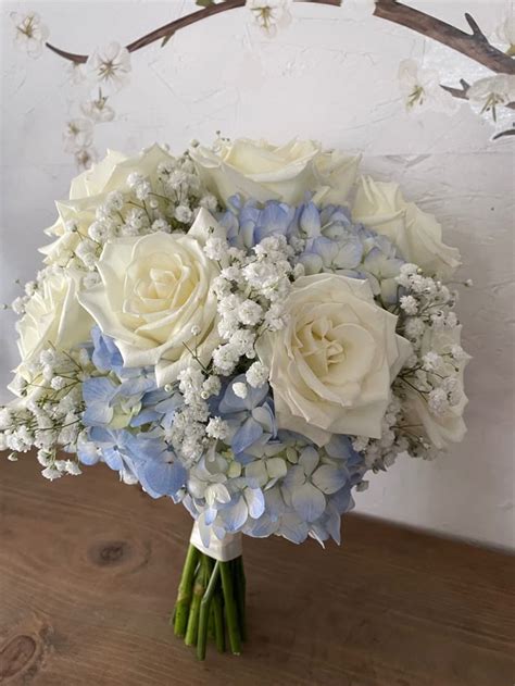 A Bouquet Of White And Blue Flowers Sitting On Top Of A Wooden Table