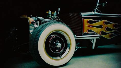 An Old Model Car With Flames Painted On It S Front Wheel And Tire Rims