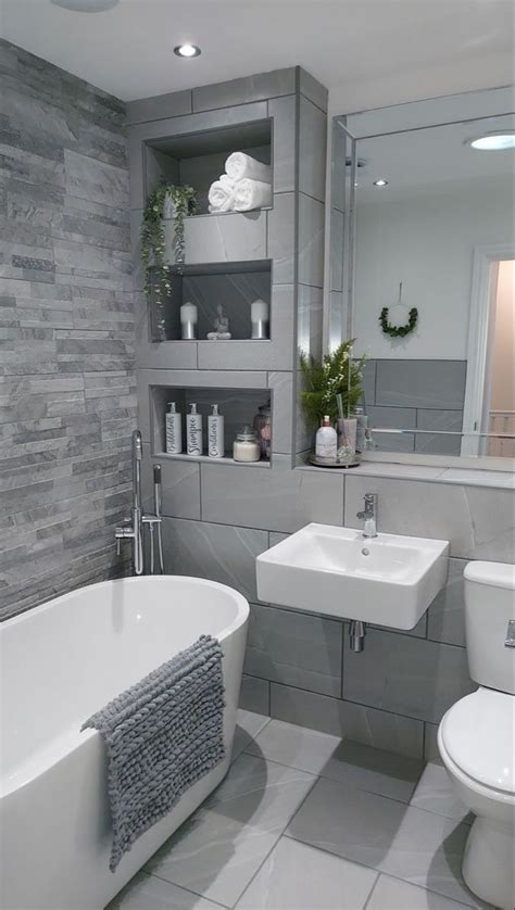 A White Bath Tub Sitting Next To A Toilet Under A Bathroom Mirror Above