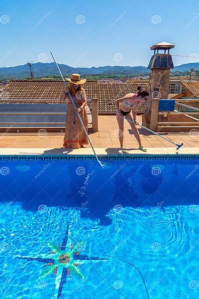 Two Lesbian Couple Friends Smiling And Cleaning A Swimming Pool Together Dressed In Summer