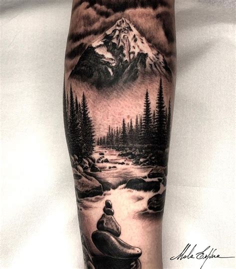 A Man S Arm With A Mountain And River Scene Tattoo On The Left Forearm