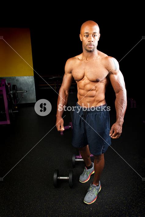 Portrait of a lean toned and ripped muscle fitness man under dramatic ...