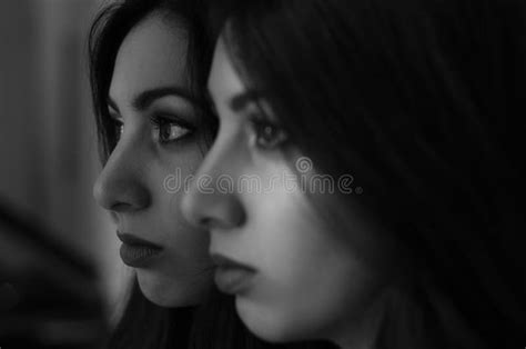 Young Charming Brunette Girl Looks At Her Reflection In The Mirror