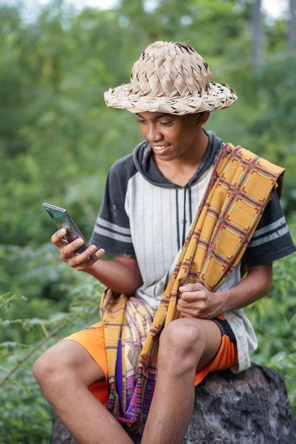 Un Hombre Con Sombrero De Paja Se Sienta En Un Tronco En Un Campo Y