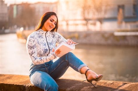 Uma morena latina na cidade ao pôr do sol à beira do rio o sol ao fundo Foto Premium