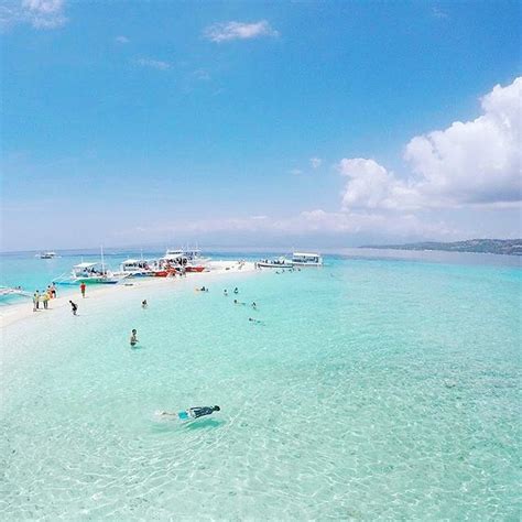 people are swimming in the clear blue water on a tropical beach with ...