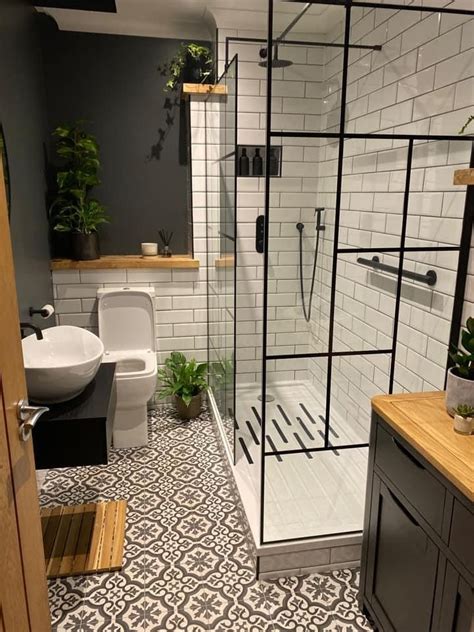 a bathroom with black and white tile flooring, a toilet, shower stall ...