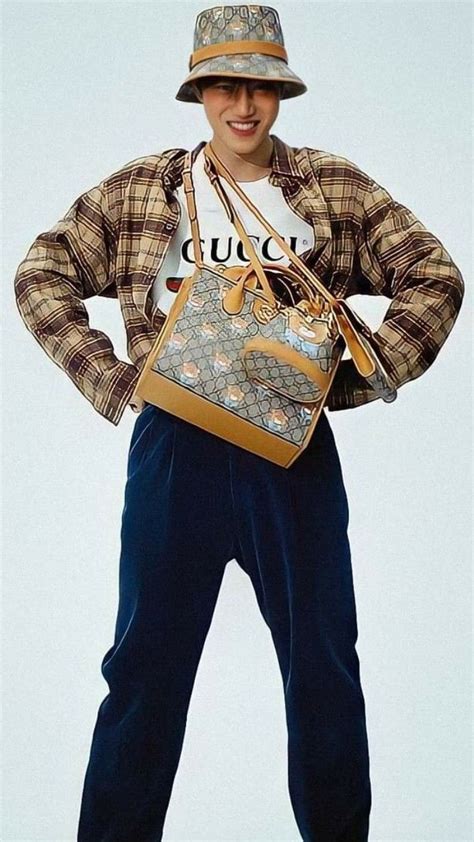 A Man Is Holding A Gucci Bag While Standing With His Hands On His Hips