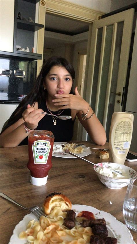 A Woman Sitting At A Table In Front Of A Plate Of Food With Ketchup