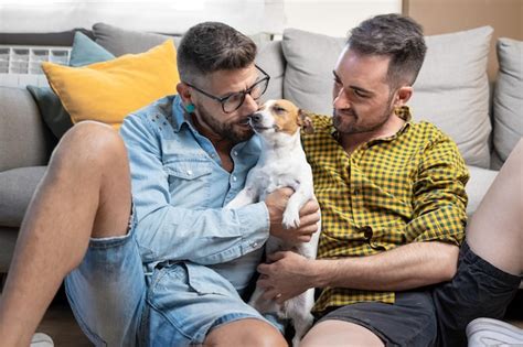 Feliz Pareja Gay Sentada En El Suelo Y Jugando Con El Perro En Casa Foto Premium