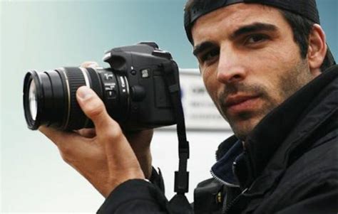 A Man Holding Up A Camera In Front Of His Face And Looking At The Camera