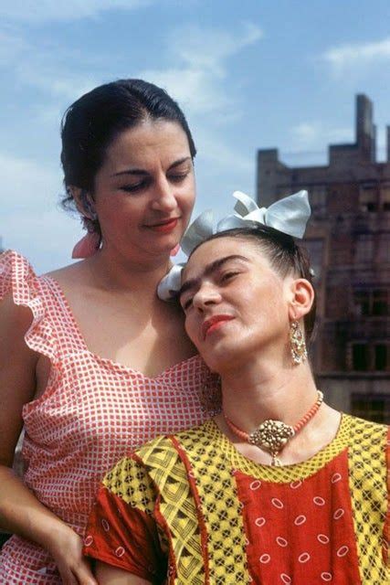 Two Women Standing Next To Each Other In Front Of A Building With A Sky