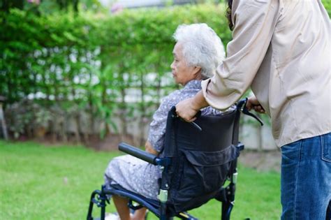 El cuidador ayuda a una anciana asiática con discapacidad a una