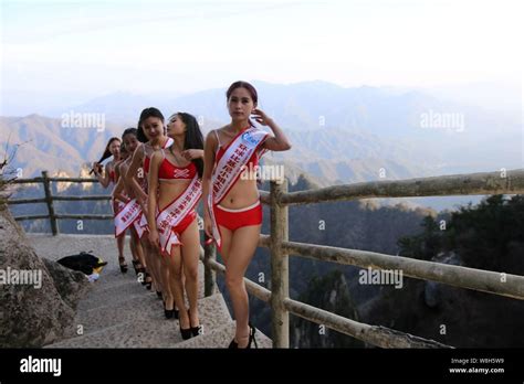 Bikini Dressed Models Pose For Photos In High Heels On A Boardwalk On The Cliff Of A Mountain