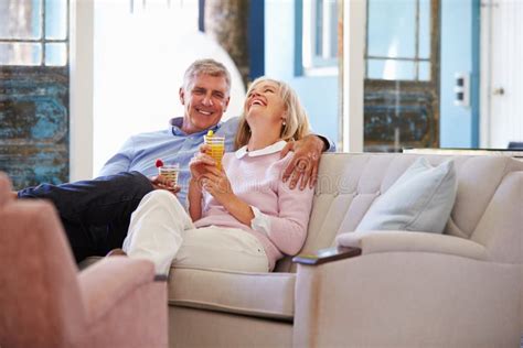 Mature Couple At Home Relaxing In Lounge With Cold Drinks Stock Image