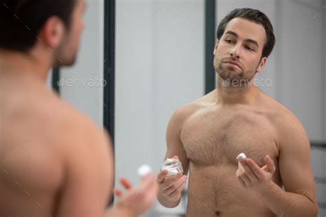 Half Naked Man Standing Near At The Mirror And Applying Shaving Foam On