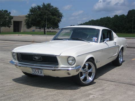 An Old White Mustang Parked In A Parking Lot