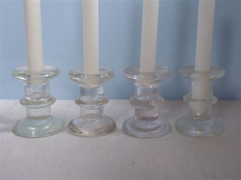 Four Glass Candlesticks Lined Up On A Table