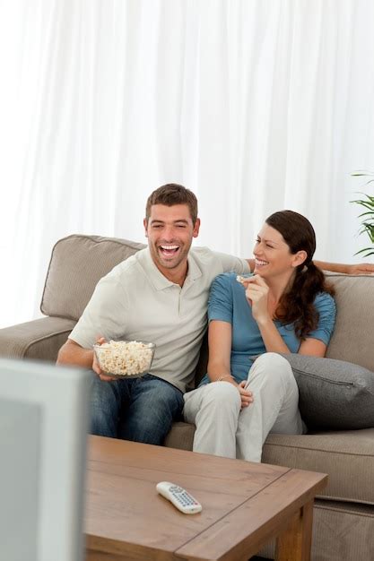 Premium Photo Cheerful Couple Eating Pop Corn While Watching A Comic