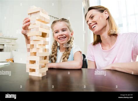 Madre e hija sonriente jugando jenga juego juntos en casa Fotografía de