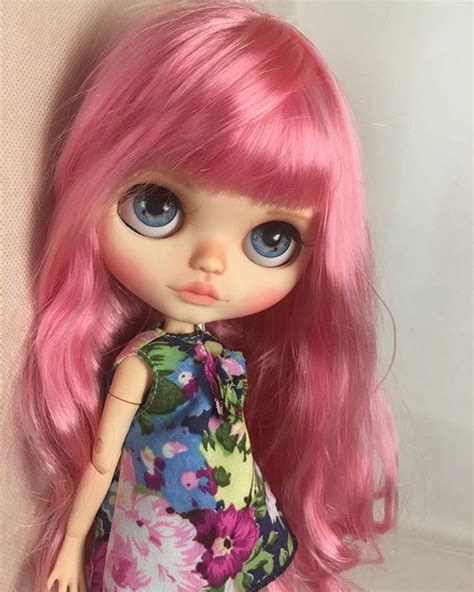 A Close Up Of A Doll With Pink Hair And Blue Eyes On A White Background