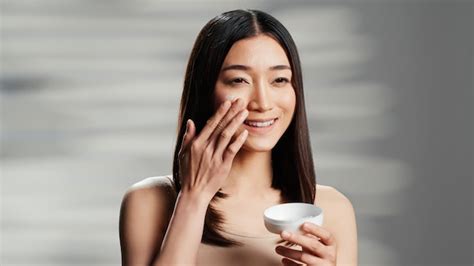 Premium Photo Asian Model Applying Facial Anti Aging Cream On Cheeks