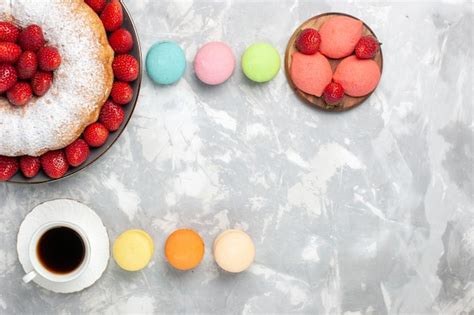 Draufsicht köstliche Erdbeerkuchen mit Tee und Macarons auf Licht