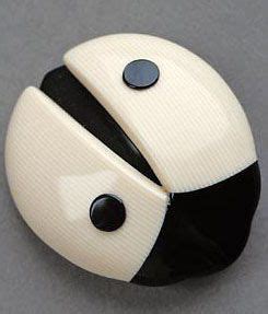 A Black And White Ladybug Brooch Sitting On Top Of A Gray Surface