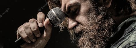 Premium Photo Man With A Beard Holding A Microphone And Singing