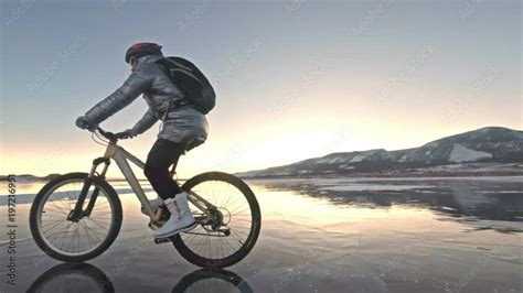 Vidéo Stock Woman is riding bicycle on the ice. The girl is dressed in ...