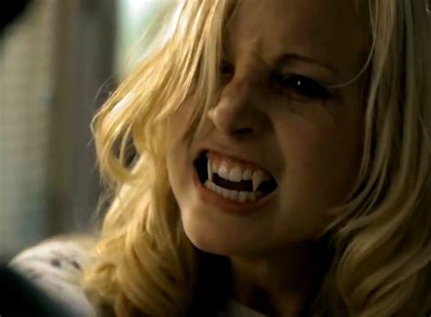 A Blonde Woman With Fangs On Her Teeth