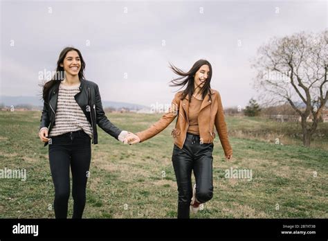 Twin Sisters Holding Hands And Laughing Outdoors Stock Photo Alamy