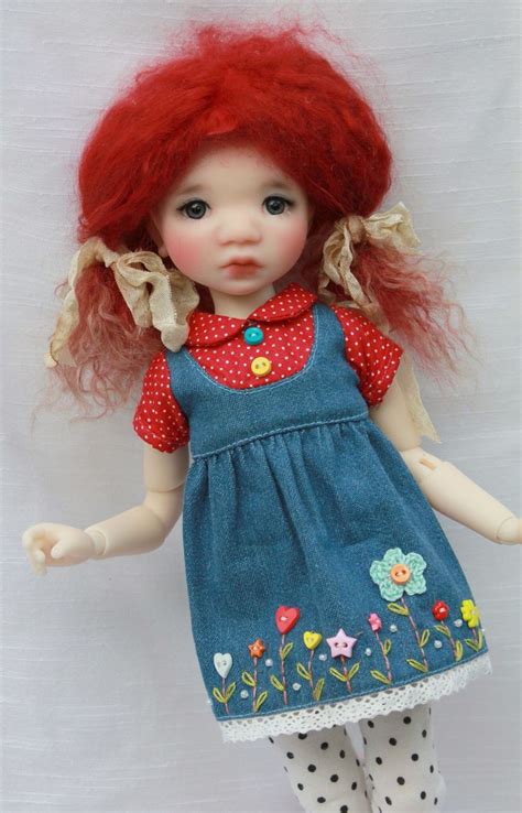 A Doll With Red Hair Wearing A Blue Dress And Polka Dot Tights Is Posed