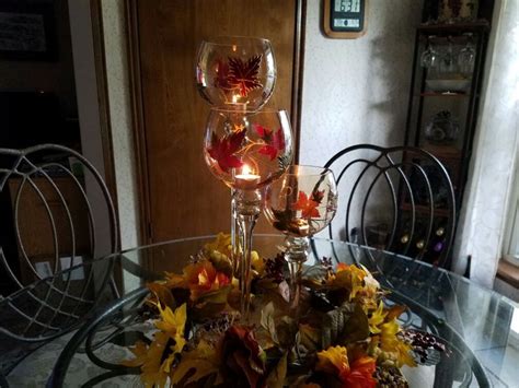 Two Wine Glasses Sitting On Top Of A Glass Table Covered In Autumn