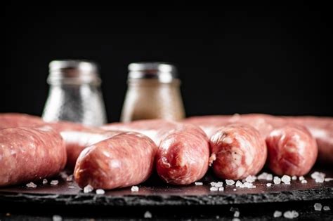 Salchichas Crudas En Un Tablero De Piedra Con Especias Foto Premium