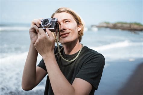 Joven fotógrafo masculino guapo en la playa Foto Premium