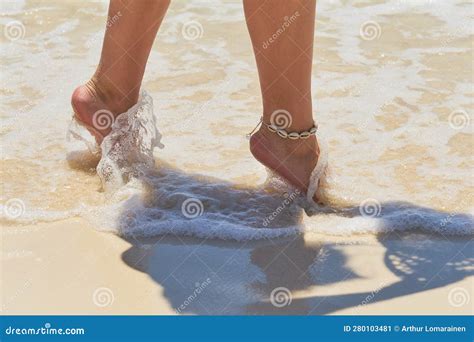 Tanned Legs Of A Woman On A Tropical Sandy Beach With Blurry Waves In