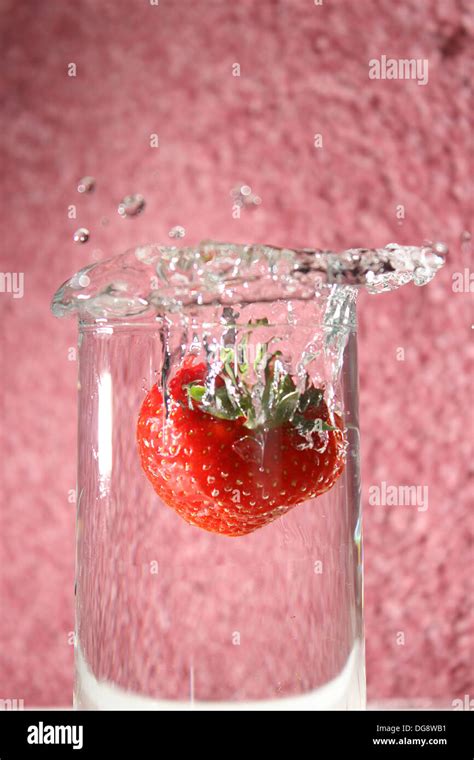 Strawberry Dropped In A Glass Of Water Creating A Splash Stock Photo