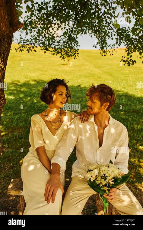 Just Married Couple Sitting Under Tree And Looking At Each Other