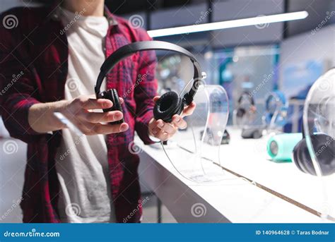 Man Holds Black Headphones In The Background Of The Store Buying