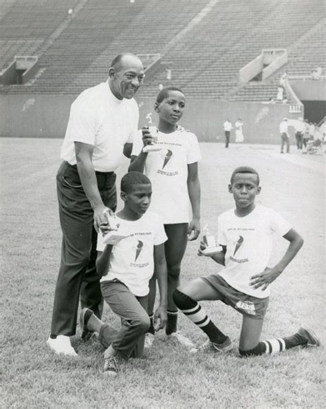 Jesse Owens poses with three young trophy winners at a track meet ...