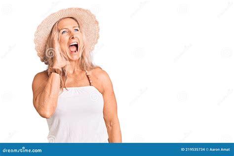 Middle Age Fit Blonde Woman Wearing Summer Hat Shouting And Screaming