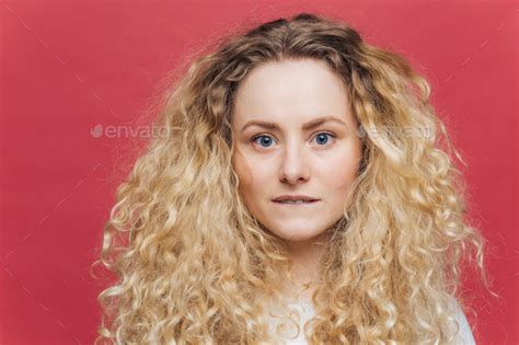 Headshot Of Beautiful Curly Blonde Female With Blue Eyes Healthy Skin Bites Lower Lip Stock