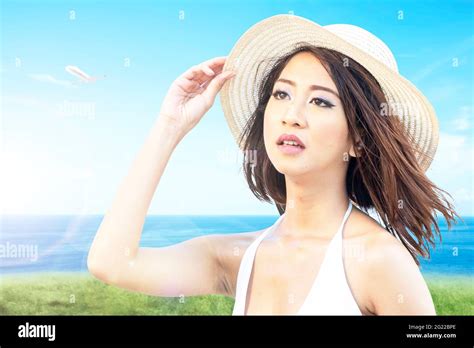 Asian Woman With Bikini And Hat Relaxing On The Field With Ocean View Stock Photo Alamy