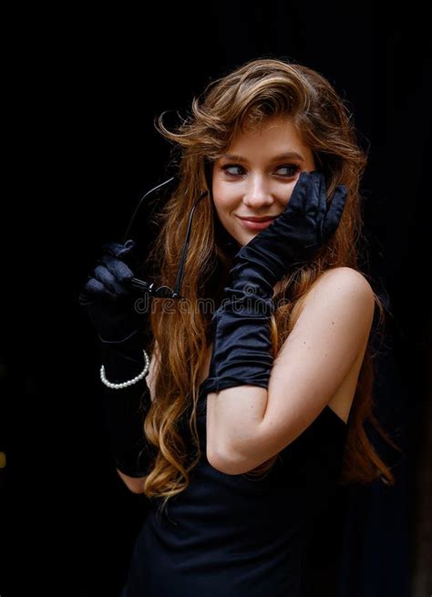 A Beautiful Caucasian Girl In A Black Dress And Sunglasses Poses Stock