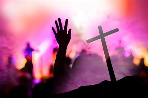 A Person Raising Their Hands In Front Of A Cross