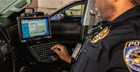 A Police Officer Sitting In The Driver S Seat Of A Vehicle Using A