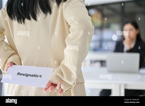 Close Up Image Of A Female Office Worker Hiding A Resignation Letter Behind Her Back While