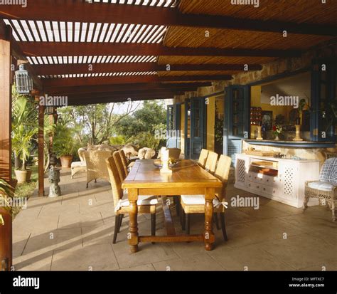 Veranda with wooden roof stone flooring dining table and chairs and ...